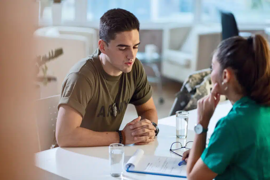 Young army soldier talking with doctor during his therapy.