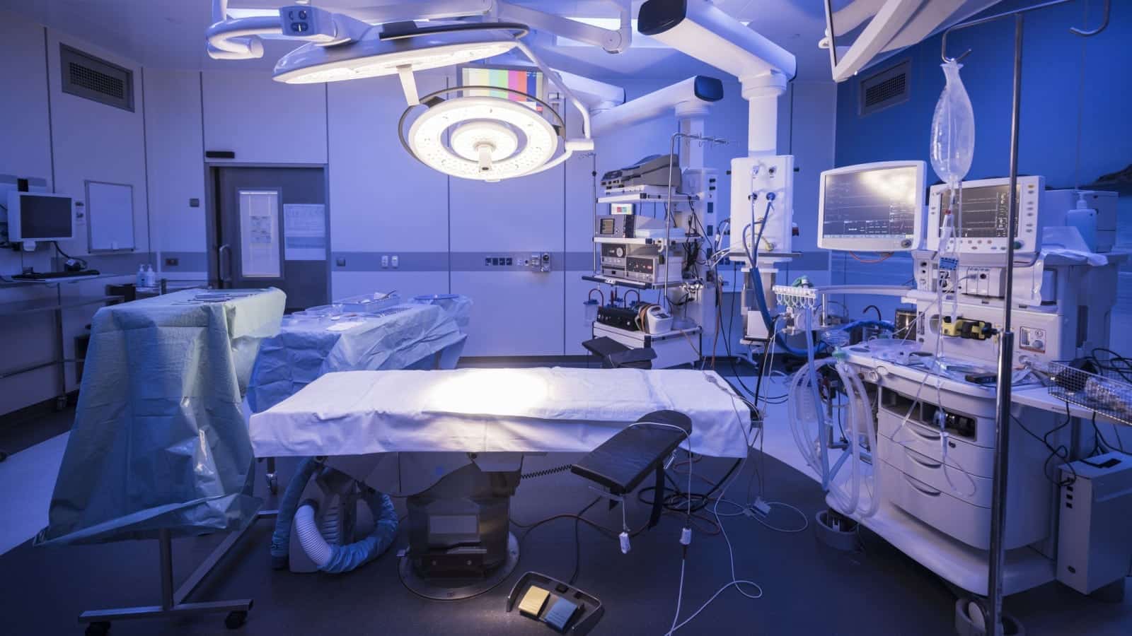 Empty hospital operating theatre with lighting over bed